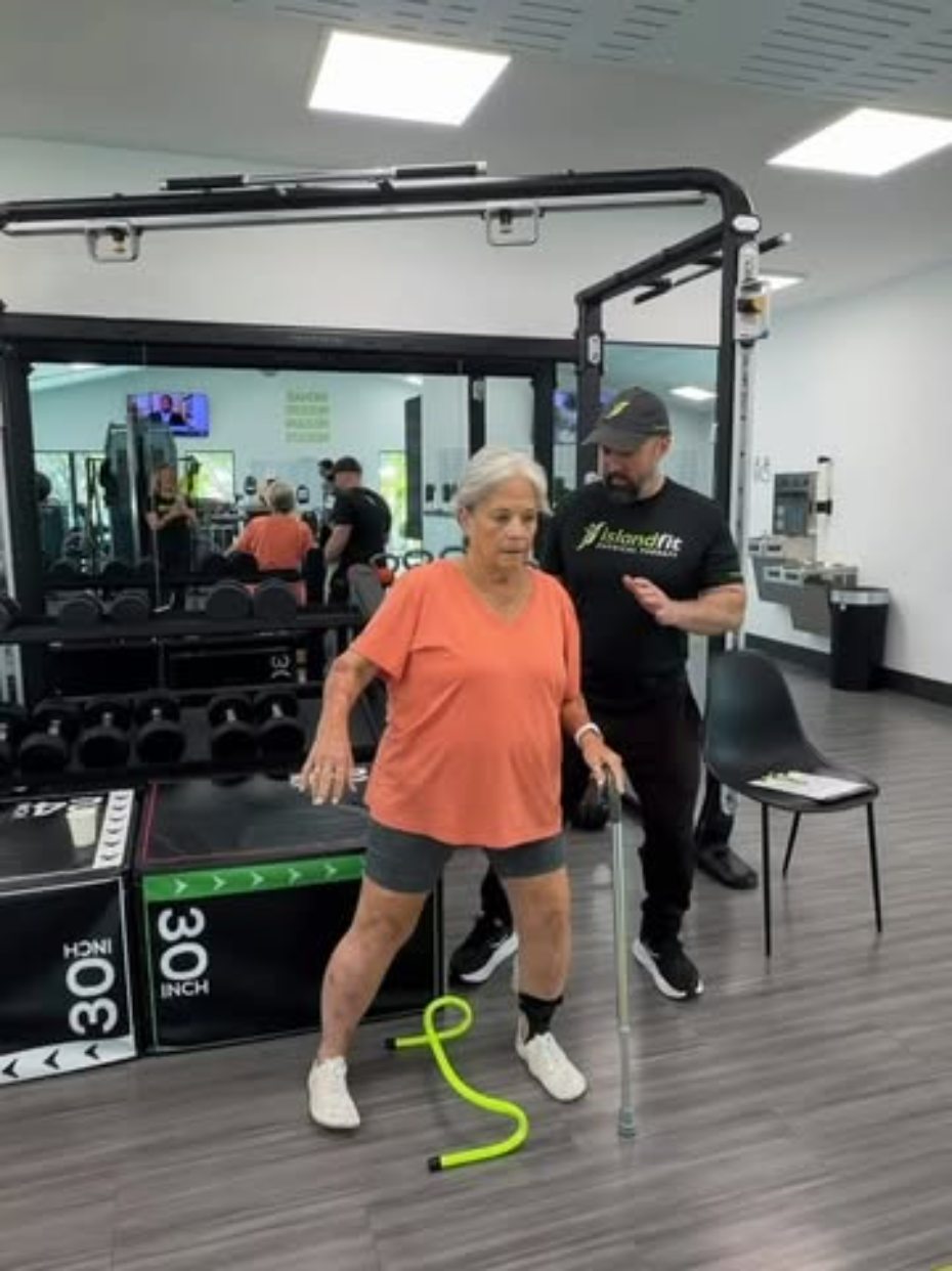 An IslandFit therapist guiding an older patient through a balance exercise