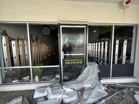 The clinic entrance with the IslandFit logo and phone number on the door, debris outside
